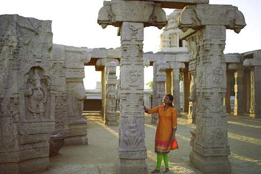 Young woman posing in the ruined premises of an ancient temple at Lepakshi, Andhra Pradesh. The temple was built in 1538 CE and a popular tourist attraction in South India.