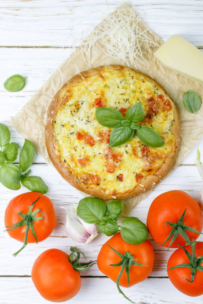istock Baked flat bread with tomatoes, cheese, garlic and Basil on a white wooden table. Rustic style. Top view. 802013674