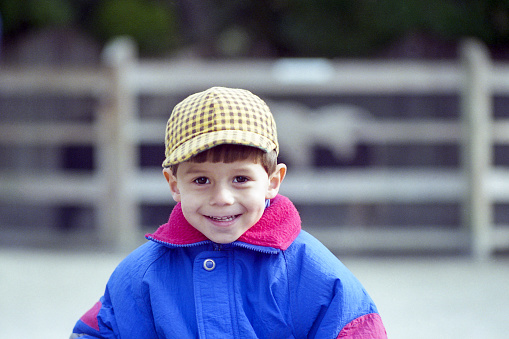 Young boy, with checkered cap, exploring petting zoo.








