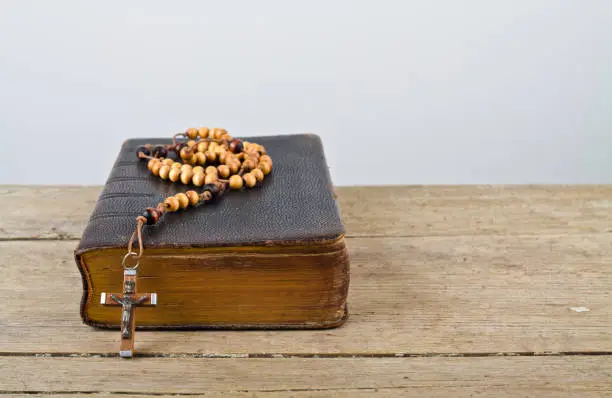 The book of Catholic Church liturgy and rosary beads on the wooden table