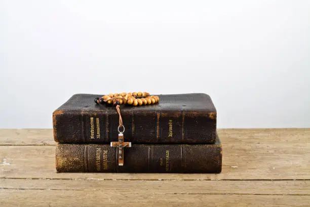 The books of Catholic Church liturgy and rosary beads on the wooden table