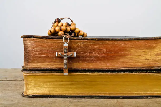 The books of Catholic Church liturgy and rosary beads on the wooden table