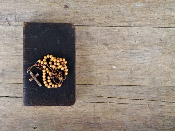 The book of Catholic Church liturgy and rosary beads on the wooden table