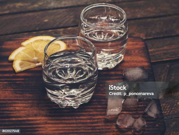 Gin Tonic Vodka Or Rum With Ice And Lemon On Wooden Table Retro Styled Background Stock Photo - Download Image Now