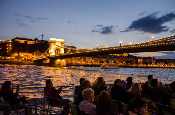 silhouette de gens assis dans un bateau de croisière sur le danube et en passant sous le pont des chaînes à une nuit d’été - budapest danube river cruise hungary photos et images de collection