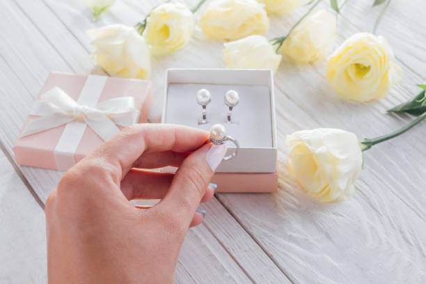 Woman opens a gift box with jewellery surrounded with flowers