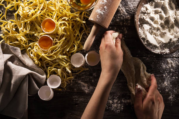 mulher cozinhar mãos preparando fazendo saborosa clássica italiana massas caseiras na mesa de madeira. closeup. vista superior. tonificação. - lifestyles domestic kitchen human hand furniture - fotografias e filmes do acervo