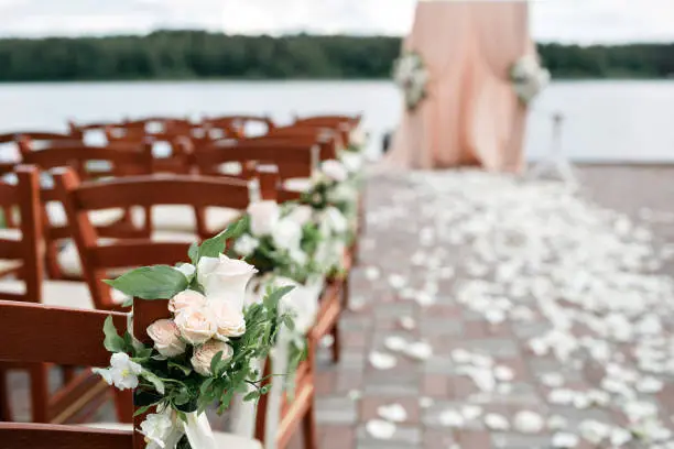 wedding arch decorated with flowers and wooden chairs on forest lake background. picture with selective focus