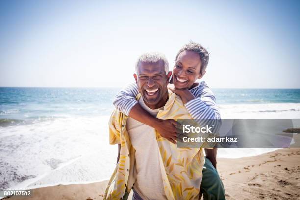 Black Couple Piggyback On Beach Stock Photo - Download Image Now - Senior Couple, Beach, Couple - Relationship