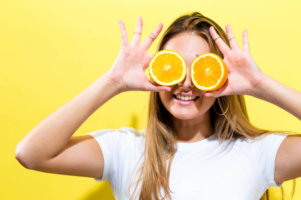 istock Happy young woman holding oranges halves 802125326