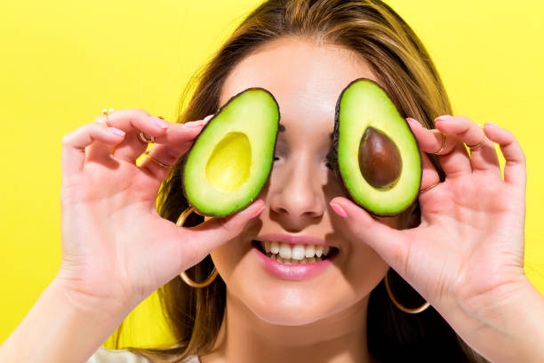 istock Happy young woman holding avocado halves 802125334