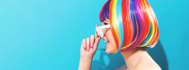 Beautiful woman in a colorful wig Beautiful woman in a colorful wig on a blue background multi coloured glasses stock pictures, royalty-free photos & images