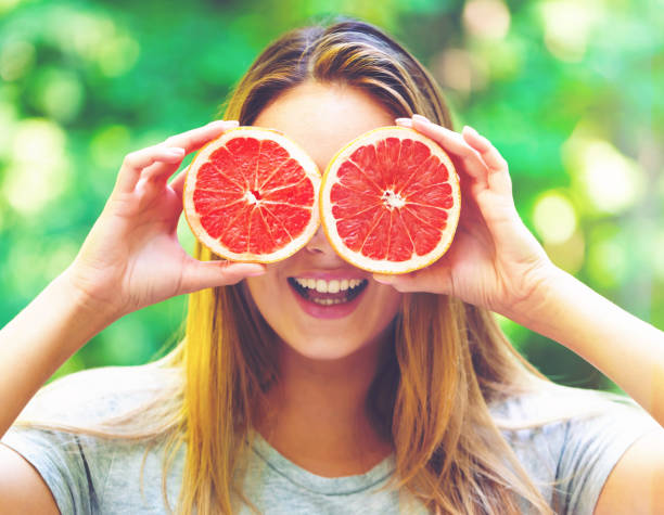 istock Happy young woman holding grapefruit 802127518