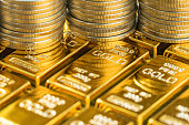 closed up shot of shiny gold bars with stack of coins as business or financial investment and wealth concept