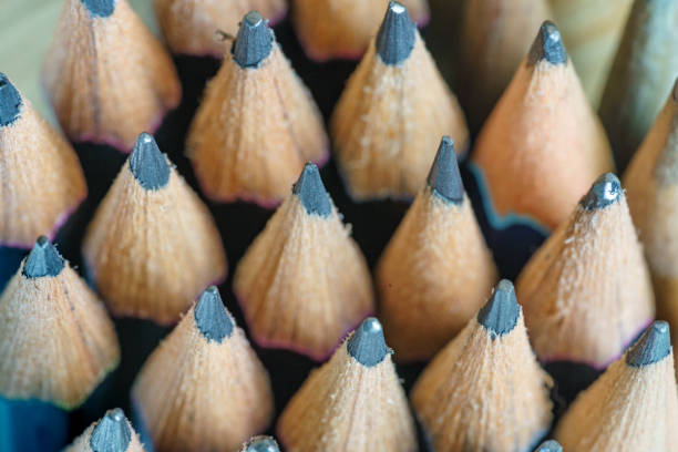 Detail of five very short, soft graphite pencils in a group with other drawing implements on white ground.
