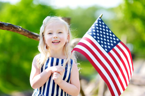 adorable little girl holding american flag outdoors on beautiful summer day - child flag fourth of july little girls imagens e fotografias de stock