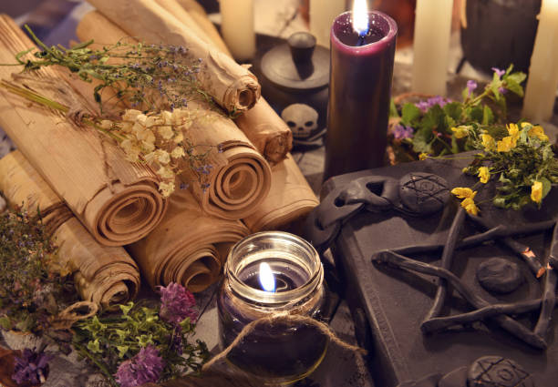 istock Black candles with old parchments and evil magic book 802161856