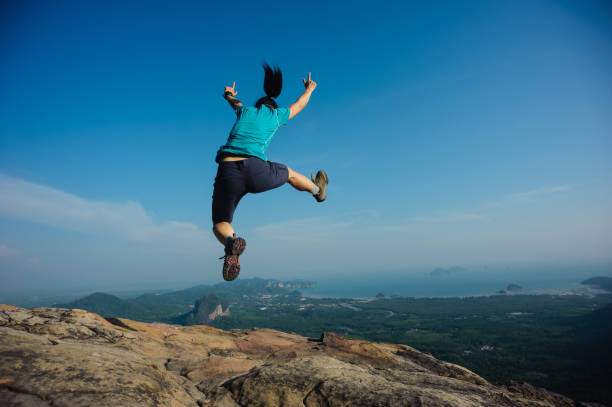 istock successful woman jumping on rocky mountain peak 802169424