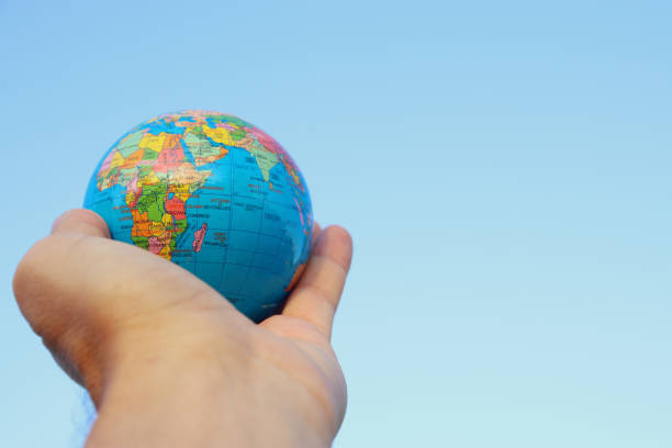 istock male hand holding small globe in front of blue sky 802175068