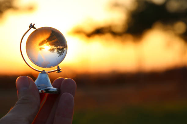 istock male hand holding small crystal globe in front of sunset 802175180