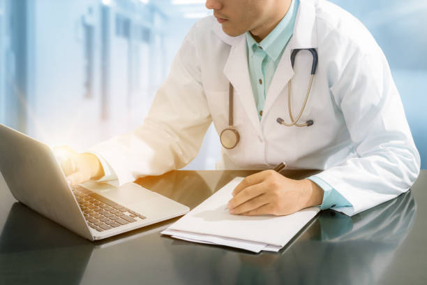 istock Doctor working on desk with laptop 802195552