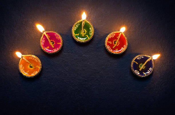 Diwali oil lamp Colorful clay diya lamps lit during diwali celebration clay oil lamp stock pictures, royalty-free photos & images