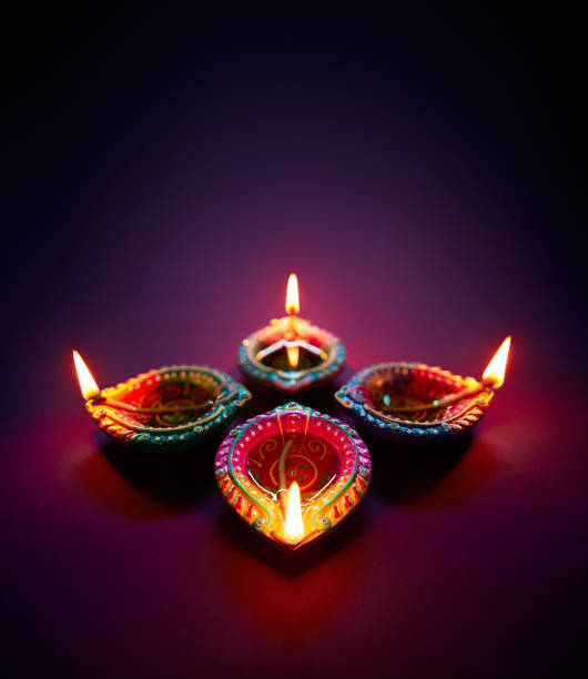 Diwali oil lamp Colorful clay diya lamps lit during diwali celebration clay oil lamp stock pictures, royalty-free photos & images
