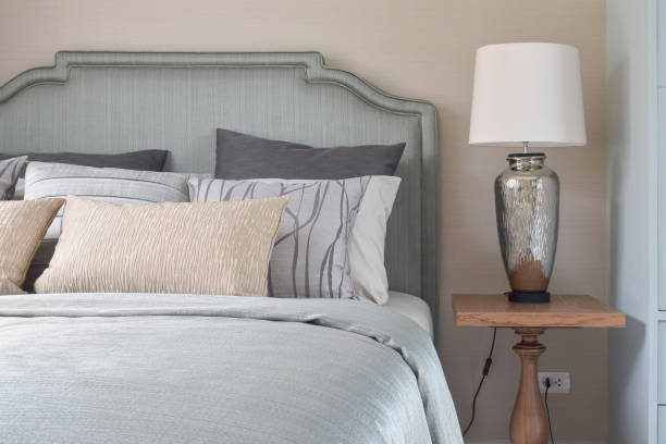 istock Romantic style bedding with satin blanket and reading lamp on wooden bedside table 802215760