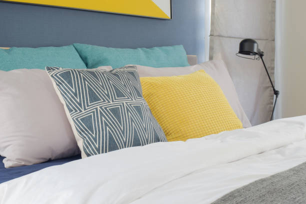 istock Yellow, gray and turquoise color pillows setting on bed in bedroom 802215794