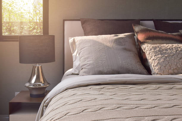 istock Elegance style pillows setting on classic style bedding and reading lamp on bedside table 802218284