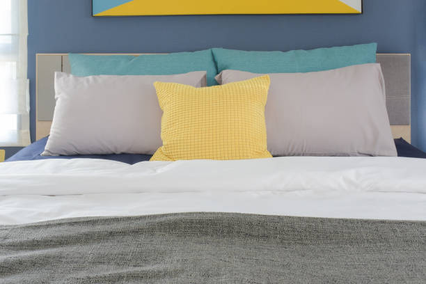 istock Yellow, gray and turquoise color pillows setting on bed in bedroom 802222544