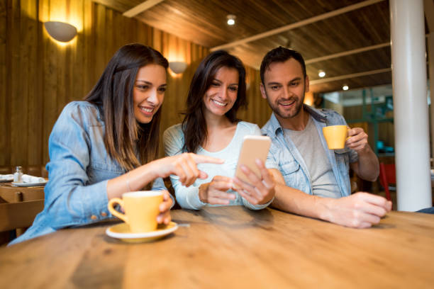 istock Friends social networking on a cell phone at a restaurant 802236448