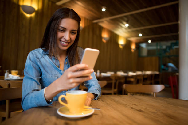 istock Woman texting on her cell phone while having a cup of coffee 802236480