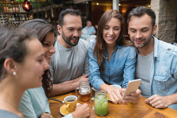 istock Happy friends looking at something on a cell phone at a restaurant 802236552