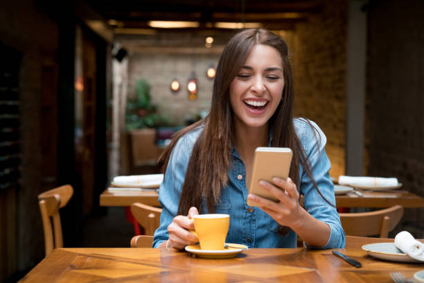istock Woman having fun social networking on her phone at a cafe 802236586