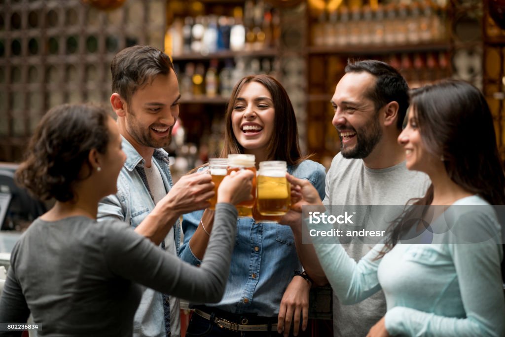 Happy group of friends making a toast at a restaurant Happy group of Latin American friends making a toast at a restaurant and drinking beers - food and drinks concepts Beer - Alcohol Stock Photo