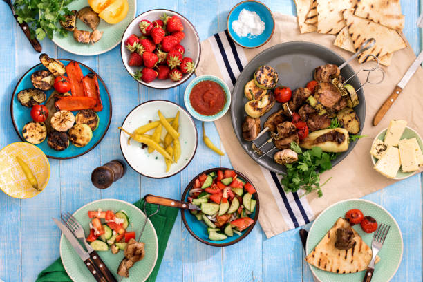 table à dîner avec shish kebab, légumes grillés, salade, collations et fraises - multi colored picnic dinner lunch photos et images de collection