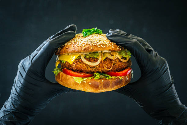 istock Tasty burger sandwich in hands weared black gloves background 802252912