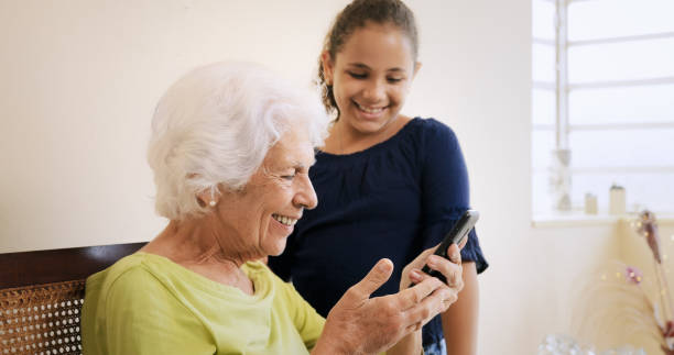 istock Girl Helps Old Woman Using Mobile Phone And Technology 802260562