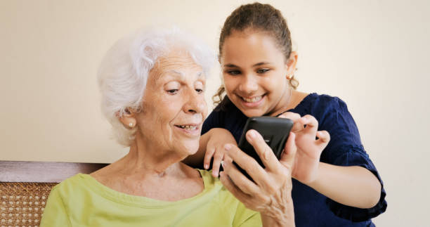istock Girl Helps Grandmother Using Mobile Phone And Technology 802260628
