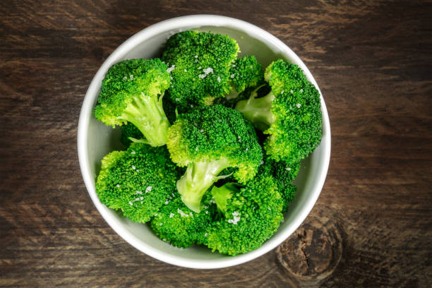 Cooked green broccoli with sea salt and copyspace A bowl of cooked green broccoli with sea salt, shot from above on a dark wooden rustic texture with a place for text broccoli photos stock pictures, royalty-free photos & images
