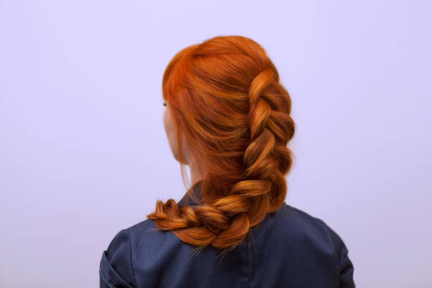 bella ragazza con lunghi capelli rossi, intrecciata con una treccia francese, in un salone di bellezza. - trecce foto e immagini stock