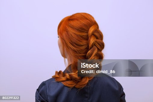istock Beautiful girl with long red hair, braided with a French braid, in a beauty salon. 802291322