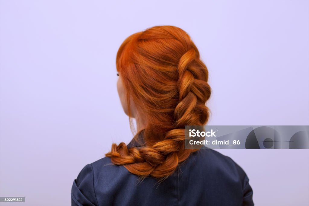 Beautiful girl with long red hair, braided with a French braid, in a beauty salon. Beautiful girl with long red hair, braided with a French braid, in a beauty salon. Professional hair care and creating hairstyles. Braided Stock Photo