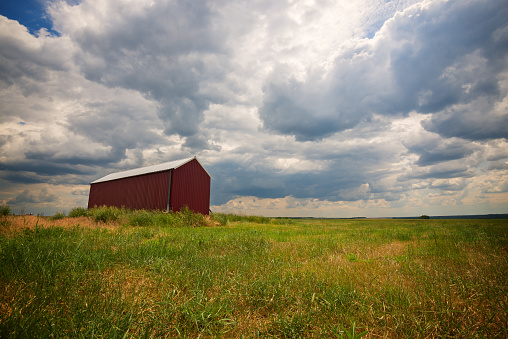 Barn, a lonely building in a field under low floating clouds. Wide angle of shooting.