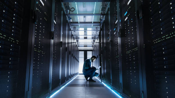 istock IT Technician Works on Laptop in Big Data Center full of Rack Servers. He Runs Diagnostics and Maintenance. 802301230
