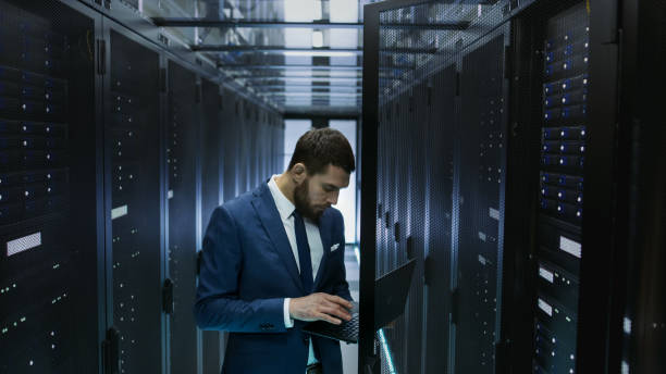 istock IT Engineer in Data Center Opens Server Rack Cabinet Door and Connects to It with His Laptop. Runs Diagnostics. 802301240