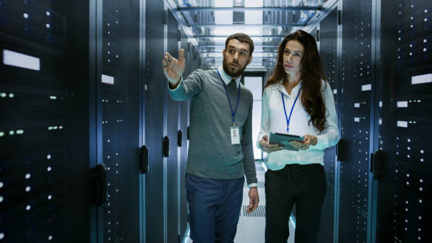 istock IT Engineer Shows Working Data Center / Server Room to Female Chief Engineer who Holds Tablet Computer. 802301286