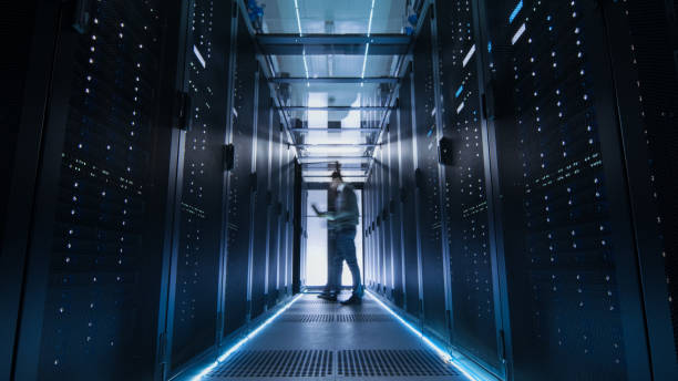 istock Male IT Engineer Walking and Working in Data Center Corridor. She is Holding Tablet Computer. He is Blurred in Motion. 802301424