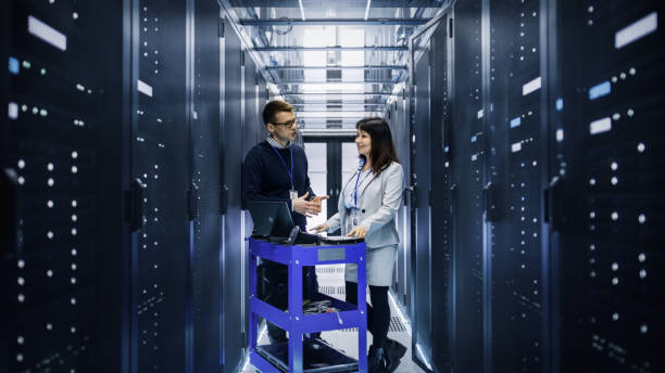 istock Caucasian Male and Asian Female IT Technicians Working with Computer Crash Cart in Big Data Center full of Rack Servers. 802301532